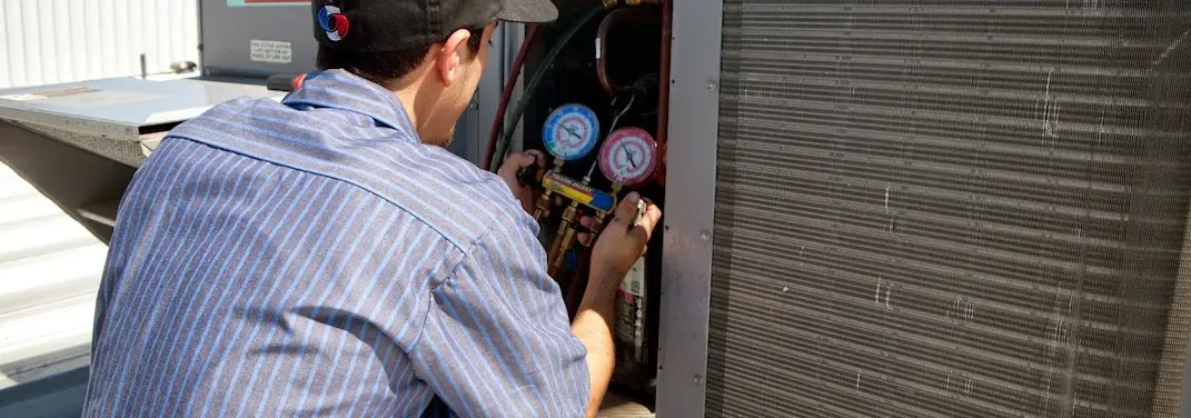 HVAC technician servicing a condenser unit in Jaffrey